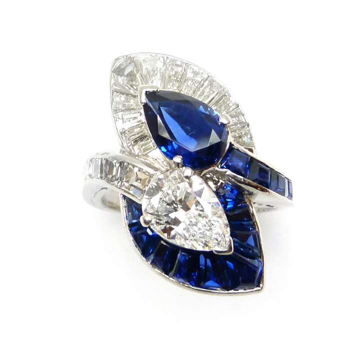 Two stone pear shaped sapphire and diamond crossover ring with leaf shaped clusters